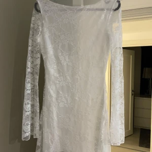 Vit spetsklänning med långa ärmar  - Säljer en vit, figurnära spetsklänning från SHEIN i storlek XS. Klänningen har långa ärmar och är tillverkad i ett tunt, genombrutet spetsmaterial med blommigt mönster. Djup rygg och rundad halsringning framtill. Köpte fel storlek därav säljs den!