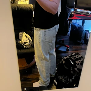 Ljusblå jeans från ASOS DESIGN - Säljer ett par ljusblå jeans från ASOS DESIGN med klassisk femficksmodell och raka ben. Jeansen har orange kontrastsömmar och normal passform. Perfekta för dig som gillar en enkel och stilren look. Lite skavda bak vid hälarna.