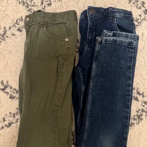 Två par byxor, ett grönt och ett blått jeans - Säljer ett par gröna byxor och ett par klassiska blå jeans. De gröna byxorna har fem fickor och normal passform, medan jeansen har en mörk tvätt och raka ben. Perfekta för dig som vill ha både stil och komfort.