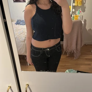 Mörkblå ribbad croppad linnetopp - Säljer en mörkblå croppad linnetopp med ribbad struktur. Toppen är ärmlös och har en rund halsringning. Perfekt för varma dagar eller att styla med jeans.