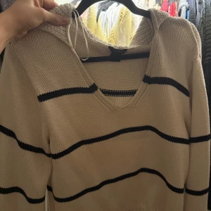 Vit stickad med svarta ränder - Vit stickad tröja från Lindex med svarta ränder. Tröjan h v-ringning och perfekt för en avslappnad och stilren look.