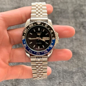 Autentisk Vintage Seiko 5 ”Batman/Batgirl” - Sällsynt och autentisk Seiko 5 ”Batman/Batgirl”. Denna klocka har blivit fullständigt restaurerad, polerad och servad av ett team proffesionella urmakare. Boettstorlek: 40mm Den är i utmärkt skick - nästintill omöjlig att skilja från en helt ny klocka. Har ett vintage automatiskt Seiko-urverk och en roterande bezel. Vid frågor eller funderingar skicka ett pm, Mvh