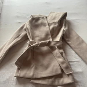 Beige kappa med luva - Snygg beige kappa med luva. Aldrig använd, var för stor.