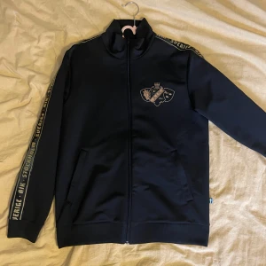 Aik Stockholm tröja Långarmad - Säljer en svart Långarmad aik tröja. Med guldiga detaljer. Storlek M. Orginal pris 600kr. Helt ny och knappast använd och säljer den för halva priset.