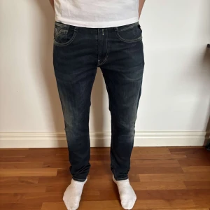Mörkblå jeansbyxor från Replay - Säljer ett par mörkblå jeansbyxor från Replay med klassisk femficksdesign och kontrastsömmar. Jeansen har normal passform och raka ben, perfekt för en stilren look. Diskret Replay-logga på bakfickan.