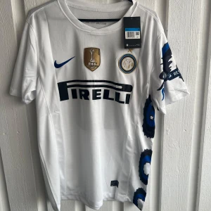 Inter Milan Sneijder 10 vit matchtröja - Inter Milan fotbollströja med Sneijder 10 på ryggen, tillverkad av lätt polyester. Vit bas med blå detaljer, Pirelli-logga och FIFA 2009-märke på bröstet. Unikt mönster i blått och svart längs sidan och ärmen, samt Champions League-märke på ärmen.