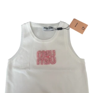 Vit linnetopp med pärlor - Supersnygg vit linnetopp med broderad logga framtill i rosa och pärlor.  Passar XS-M