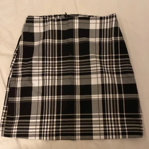 Svartvit rutig kortkjol från New Yorker - Snygg svartvit rutig kortkjol från Amisu i klassisk A-linjeform. Kjolen har dragkedja i sidan och är fodrad för extra komfort. Perfekt för dig som gillar stilrena och trendiga plagg med lite edge. Nästan aldrig använt