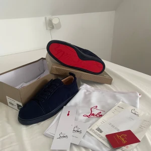 Mörkblåa loubs / Christian Louboutins - Snygga mörkblå sneakers från Christian Louboutin i mjuk mocka med klassisk röd sula och broderad logga på hälen. Skorna har rund tå, platt sula och snörning framtill. Kommer med originalkartong, dustbag och äkthetsbevis. Perfekt för dig som gillar exklusiv streetstyle. Kan mötas upp. 