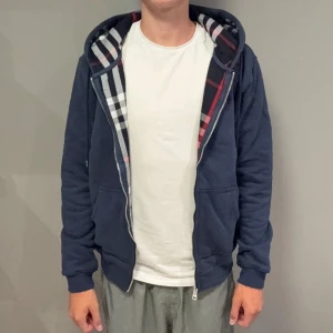 Marinblå burberry hoodie - Säljer denna riktigt feta burberry Hoodien i nyskick. Unik hoodie som inte många har med ett fett tryck på insidan av tröjan och luvan. Han på bild är 185cm, 74kg så den passar nog mer M. Hör av er vid funderingar 