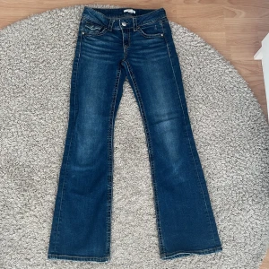 Lågmidjade Blå bootcut jeans från Gina Tricot Young - Snygga lågmidjade blå jeans från Gina Tricots Young kollektion! Jeansen är i storlek 158 med klassisk bootcut passform. Jeansen har fem fickor, dekorativa sömmar och silverfärgade knappar. Jeansen har en lätt tvättad look och kontraststickningar. Perfekt för dig som gillar retrovibbar och cool stil. Säljer då det tyvärr blivit för smet för mig! Köpta för ca 359 kr.
