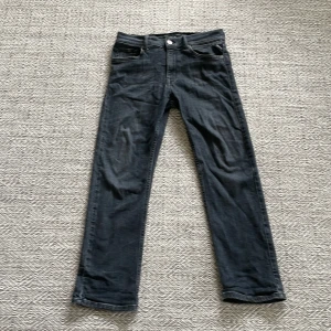 Svarta jeans från Replay Thad - Säljer ett par svarta Replay Thad jeans med klassisk femficksdesign och raka ben. Jeansen har en snygg mörk tvätt och silverfärgad knapp framtill. Passar dig som gillar stilrena och tidlösa jeans med normal passform inga defekter. Priset är inte hugget i sten. 152 i barn