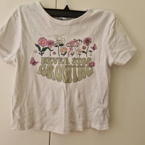 Vit t-shirt med blommor från New yorker - Vit t-shirt med blommor från New yorker i storlek S med tryck framtill. Magtröja så den är kort och liten i storleken