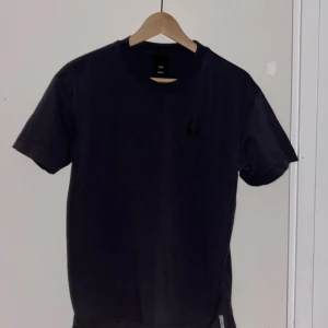 Grå t-shirt med sail racing - Snygg grå t-shirt i bomull med rund hals och korta ärmar. På bröstet finns en sail racing logga i  svart, vilket ger en unik och chill vibe. Passformen är normal och tyget känns mjukt mot huden. Perfekt för dig som gillar stilrena detaljer.