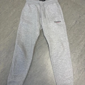 Grå mjukisbyxor från McKenzie - Snygga ljusgrå mjukisbyxor från McKenzie med broderad logga på vänster ficka. Byxorna är tillverkade i mjukt bomullsmaterial. Passformen är normal och benen är avsmalnande för en clean look.