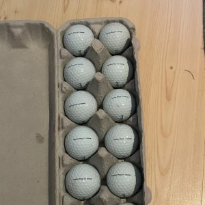 Titeliest golfbollar - Ingen bok syns på bilden, endast en äggkartong fylld med golfbollar. Ingen information om titel, författare eller bokinnehåll kan utläsas från bilden.