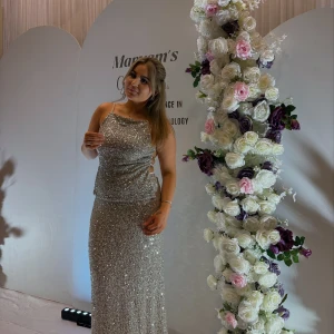 Glittrig silver topp med matchande kjol - Säljer en superglittrig silverfärgad topp med klänning med smala axelband och öppen rygg med snygga banddetaljer. Klänningen har en figurnära passform och är täckt av paljetter som verkligen fångar ljuset. Perfekt för dig som vill sticka ut och glänsa på bal eller fest!