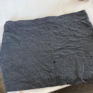 Mörkgrå basic kjol från H&M - Enkel mörkgrå kjol från H&M Basic, rak modell i mjukt stretchigt tyg. Kjolen är tillverkad av viskos, bomull och elastan för en bekväm passform. Perfekt till sneakers eller boots för en chill look.