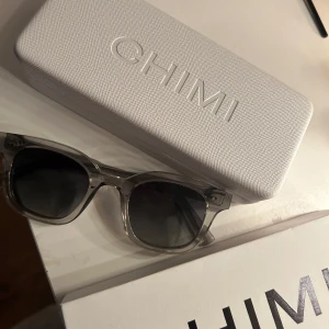 Grå transparenta CHIMI solglasögon - Snygga solglasögon från CHIMI med transparent grå båge och svarta glas. Modellen har en klassisk fyrkantig form och coola detaljer på skalmen. Kommer med originalfodral och putsduk. 🫶🏽