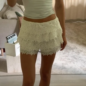 Vita spets-shorts från Zara Woman - Supersöta populära vita shorts från Zara med blommig spets och volangdetaljer. De är högmidjade och har en dold dragkedja i sidan! Storlek S
