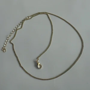 Guldigt kedjehalsband med justerbar längd - Snyggt halsband i guldton med klassisk kedjedesign och justerbar längd tack vare förlängningskedjan. Perfekt att bära som det är eller att kombinera med andra smycken för en cool layering-effekt. 