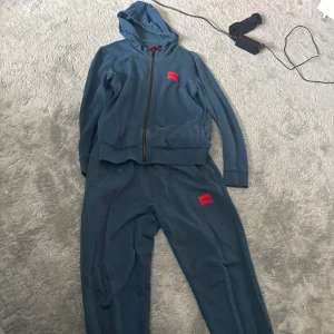 Blå Hugo dress - Säljer mitt blåa Hugo sätt storlek s i kofta m i byxor. Mycket bra skick och bra nu till hösten om du vill ha en snygg outfit 