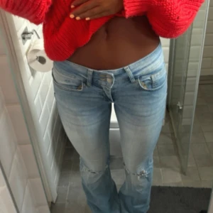 Ljusblå Nelly bootcut jeans med slitningar - Säljer ett par ljusblå jeans med låg midja och bootcut passform. Jeansen har snygga slitningar vid knäna och klassiska fem fickor. Perfekta för dig som gillar en avslappnad och trendig stil. Materialet är jeans och de har en riktigt skön vibe.