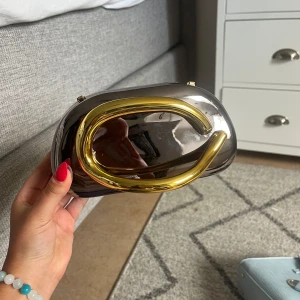 Metallic kuvertväska med gulddetalj - Snygg snygg trendig väska som aldrig använts (har en guldkedja dessutom så man kan hända den över axeln) !! 