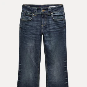 Low Bootcut jeans i mörkblå denim - Snygga bootcut jeans i mörkblå tvätt med klassiska fem fickor och kontrastsömmar. Jeansen har en lätt slitning längs benen och en bredare benslut för en cool retrostil. Perfekta för dig som gillar en avslappnad men trendig look.