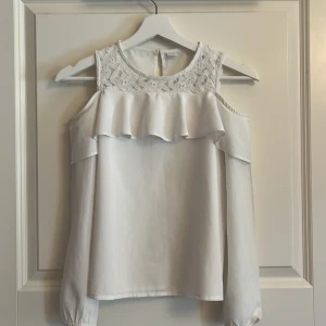 Söt vit blus med spets och volang❤️ - Supersöt vit blus med spets upptill och volangdetalj över axlarna. Blusen har offshoulder-design med långa ärmar och knäppning bak i nacken. Materialet känns lätt och har en fin struktur, perfekt för dig som gillar romantiska vibes. Finns lite små fläckar som går bort i tvätten. För övrigt en jätte söt topp som jag använt till fester, fin middagar mm.💓💓