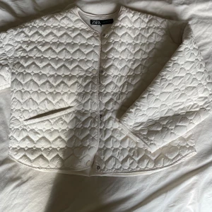 Höst jacka från Zara - Höst jacka från Zara i vit färg med hjärtformade sömmar. Jackan har rund hals, tryckknappar framtil. Perfekt för dig som gillar stilrena detaljer och vill ha något som sticker ut.