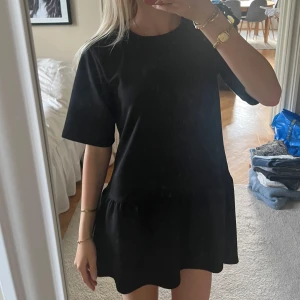 Svart kort volangklänning - Supersöt svart klänning med volang nedtill och rund hals. Klänningen är såå mjuk och bekväm 💓💓💓💓använd endast en gång! 