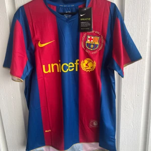 Barcelona Deco 20 Nike fotbollströja - Säljer en officiell FC Barcelona matchtröja från Nike med Deco och nummer 20 på ryggen. Tröjan har breda röda och blå vertikala ränder, gul Unicef-logga och klubbmärke på bröstet. Kortärmad modell i lätt och ventilerande polyester, perfekt för fotboll eller samling.