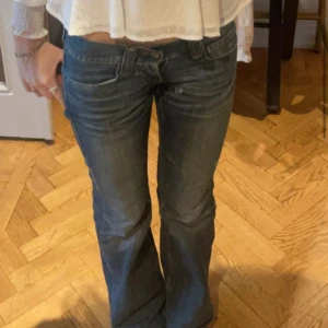 Blå bootcut jeans från Fornarina - Säljer ett par blå jeans från Fornarina som är lågmidjade med bootcut-modell och snygga slitningar. Jeansen har klassiska fickor, kontrastsömmar och en läderpatch bak.