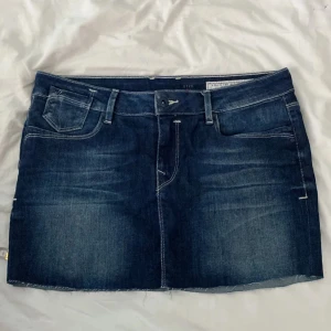 Mörkblå jeanskjol från edc - Snygg mörkblå jeanskjol från edc med klassiska fickor fram och bak, bälteshällor och rå kant nertill. Kjolen har en rak passform och coola detaljer som kontrastsömmar och knappar på bakfickorna. Perfekt för dig som gillar en avslappnad men trendig stil. Klippt då den va för lång för min smak men går jättebra att klippa mer om man önskar. Skriv vid frågor💕