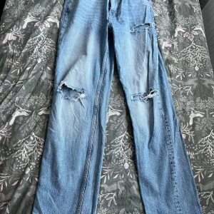 Ljusblå ripped jeans från Gina Tricot - Säljer ett par ljusblå jeans från Gina Tricot med raka ben och slitna detaljer på knäna. Jeansen har klassisk femficksdesign och är tillverkade i bomullsdenim. Vid frågor hör av dig!