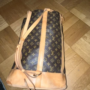 Louis Vuitton monogram resväska - Säljer en klassisk Louis Vuitton resväska i brunt monogrammönster med ljusbruna skinn-detaljer. Väskan har justerbar axelrem, dragkedjeficka på insidan och rymligt fack. Perfekt för dig som vill resa med stil och visa upp en ikonisk design.