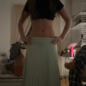 Ljusgrön plisserad långkjol - Säljer en superfin ljusgrön långkjol med plisserade veck. Kjolen har en flowy känsla och hög midja, perfekt att styla med crop tops eller stickade tröjor. Enkel att matcha och ger en fräsch vibe till din outfit.