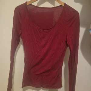 Mörkröd långärmad topp - Enkel och stilren mörkröd långärmad topp med rundad urringning. Tunn och mjuk i materialet, perfekt att bära som lager eller för en clean look. Passar dig som gillar basic men ändå vill ha lite färg i garderoben. 