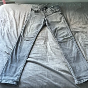 Ljusgrå jeansbyxor 32/32 - Snygga ljusgrå jeansbyxor i klassisk femficksmodell. Jeansen har raka ben och normal passform, perfekta för en clean och avslappnad look. Tillverkade i mjukt denimtyg som är skönt att bära hela dagen.