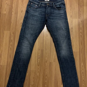 Mörkblå jeans från Jack & Jones - Snygga mörkblå jeans från Jack & Jones med snygga diskreta slitningar framtill. Jeansen har raka ben och kontrastsömmar på bakfickorna. Perfekta för dig som gillar en stilren look. Skick 10/10. Storlek 30/32. Priset kan absolut diskuteras. Hör av er för fler frågor eller bilder.