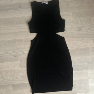 Svart cut out klänning från NA-KD - Säljer en svart, tight kortklänning från NA-KD med cut out-detaljer i midjan. Klänningen har aldrig används.