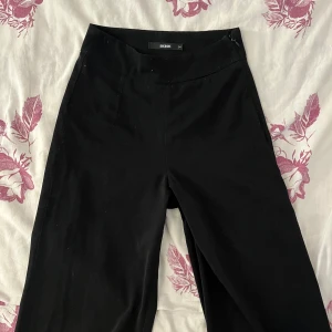 Svarta kostymbyxor från Bik Bok - Stilrena svarta kostymbyxor från Bik Bok i klassisk rak modell. Byxorna har hög midja och dold dragkedja i sidan. De är i storlek XS och säljer pga ingen användning. Skriv för fler bilder eller funderingar
