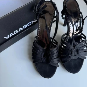 Svarta sandaler med klack  - Svarta sandaler med snygga remmar och öppen tå. Skorna har hög klack och smala remmar som går runt foten. Skorna har en rund tå. Enkla att gå i och super söta.