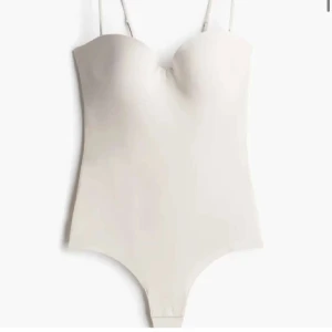 Vit hm body med smala band - Säljer en stilren vit body med smala axelband. Liten i storleken!!Toppen har en tight passform och är perfekt att styla med jeans eller kjol. Enkel och clean design som passar till många olika looks.