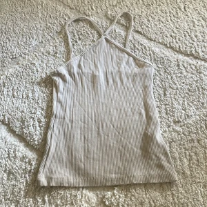 Beige ribbad linnetopp - Säljer en beige ribbad linnetopp med smala axelband och rak passform. Materialet känns mjukt och stretchigt.