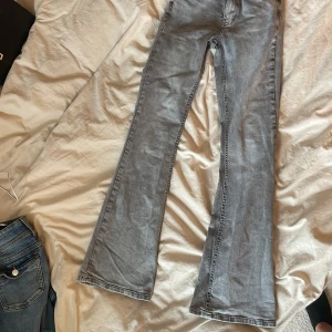 Grå bootcut jeans från Gina Tricot - Snygga grå jeans från Gina Tricot, modell Perfect Jeans. De har bootcut-ben och klassisk femficksdesign. Jeansen är i ett mjukt denimtyg och har en ljusgrå tvätt som ger en chill vibe. Perfekta till sneakers eller boots.