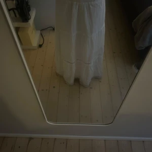 Vit Maxi kjol  - Säljer en superfin vit långkjol med volangdetaljer och broderade inslag. Kjolen har en luftig och flowy passform, perfekt för varma dagar. Resår i midjan gör den bekväm och enkel att bära.