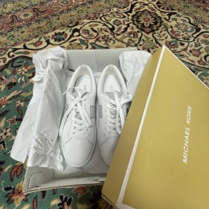 Vita sneakers från Michael Kors med glitter - Snygga vita sneakers från Michael Kors med glittriga silverdetaljer på sidor och häl. Perfekta för dig som vill ha en clean look med lite extra bling. Säljer pga passade inte mig. Pris går att diskutera 🥰