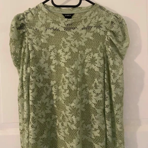 Grön spetsblus - Säljer en ljusgrön blus från Lindex med blommigt spetsmönster. Blusen passar perfekt till sommaren nu och färgen är jättefin. 